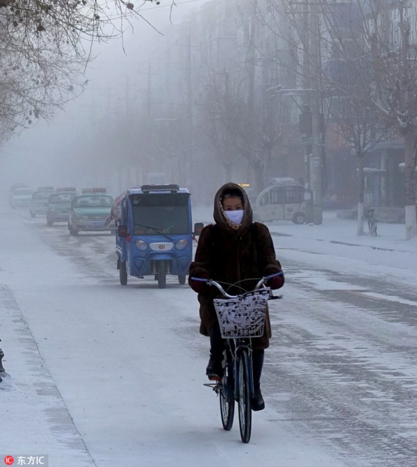 12月13日，内蒙古呼伦贝尔市牙克石街头冰雾弥漫，能见度很低，人们在严寒中出行。