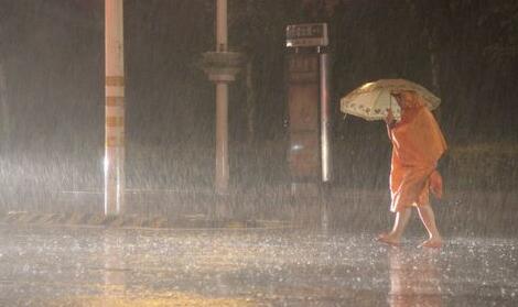 19日夜间,急雨突袭临沂城区,一位行人身披雨衣撑伞在雨中艰难前行.