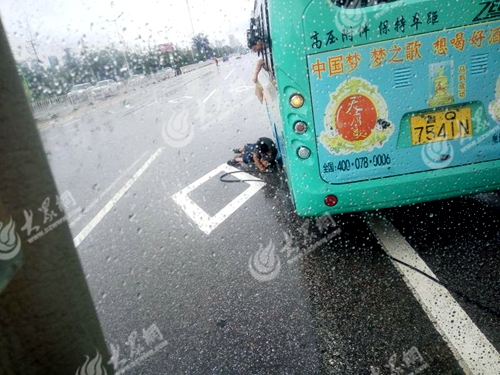 雨中温情：7月9日公交修理厂修理工王晓玻在罗庄区医院修116路鲁Q7541N，驾驶员拿着牌子给挡雨。