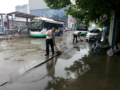 公交驾驶员在北城换乘中心停靠站清扫路面积水
